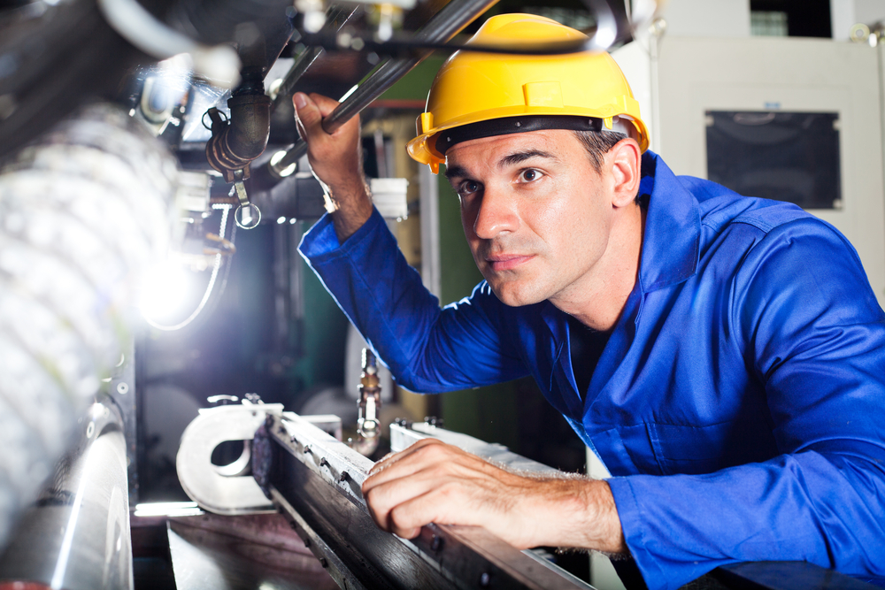 A photo of an industrial worker in a factory looking at industrial components