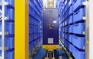 Image of Automated warehouse machine restocking blue shelf cartons.